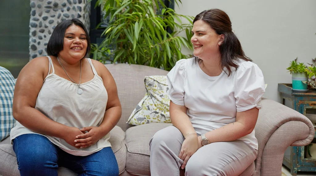two women sitting on a couch smiling